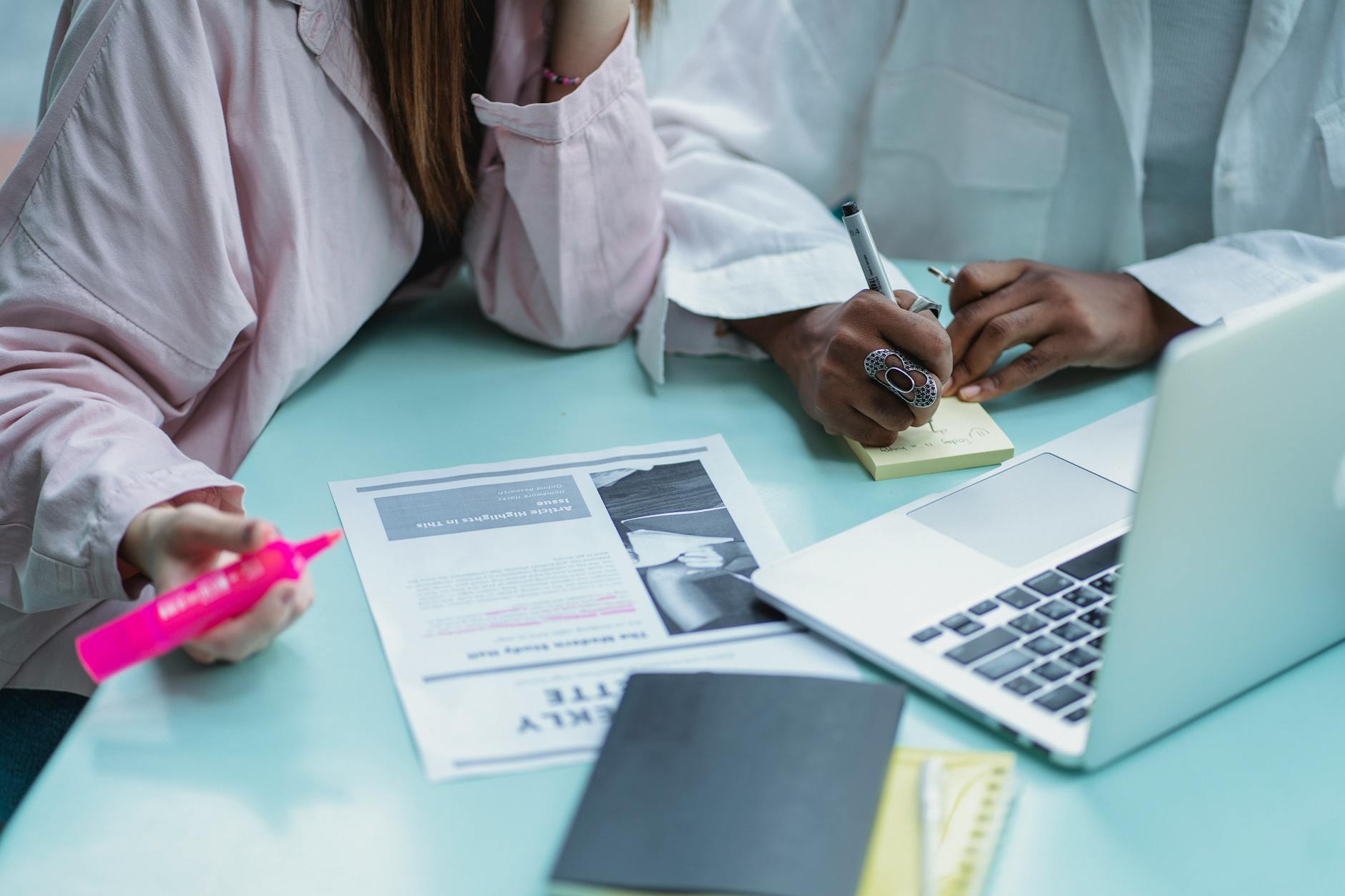 A medical student studying at a desk with notes and a laptop open to practice questions